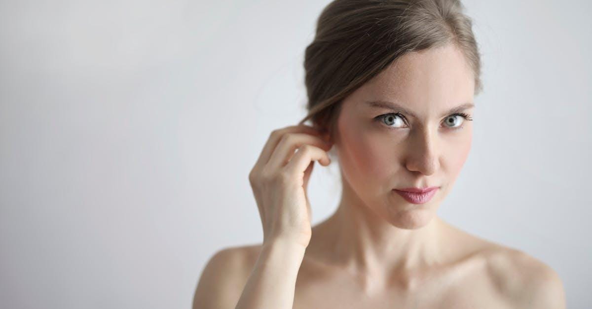 Close-up portrait of a young woman with natural makeup, showcasing elegance and beauty with a soft white background.
